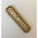 A rectangular gilt and MOP brooch with scroll deco