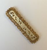 A rectangular gilt and MOP brooch with scroll deco