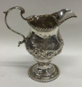 A Georgian silver embossed cream jug decorated wit