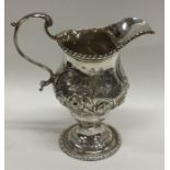 A Georgian silver embossed cream jug decorated wit