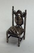 A miniature silver doll's house chair with swirl d