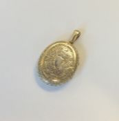 An oval silver locket engraved with flowers and le