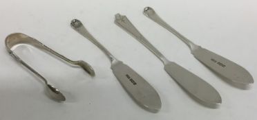 A pair of silver butter knives together with sugar