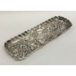 A heavy embossed silver pin tray with wavy edge. A