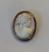 An oval coral cameo of a lady in gold frame. Appro