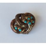 A turquoise brooch decorated with leaves in gold.