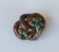 A turquoise brooch decorated with leaves in gold.