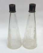 A pair of tapering glass decanters with plated top