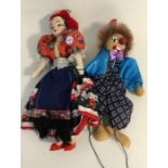 A wooden puppet of a clown together with a doll in