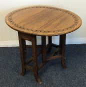 An Edwardian carved top drop leaf occasional table