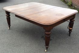 A massive oak extending table on fluted tapering s