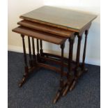 A nest of three mahogany tables on slender bases.