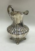 A tall Victorian silver cream jug on bracket feet.