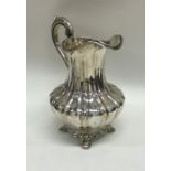 A tall Victorian silver cream jug on bracket feet.