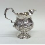 A Georgian squat silver cream jug decorated with f
