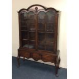 A tall Queen Anne style bookcase with shaped top t