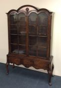 A tall Queen Anne style bookcase with shaped top t