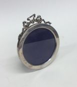 A circular silver picture frame with ribbon top. B