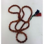 An unusual long string of amber beads with tassel