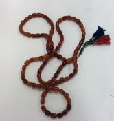 An unusual long string of amber beads with tassel