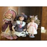 Three dressed porcelain headed dolls in pink and l