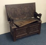 An oak hinged top settle of typical design. Est. £
