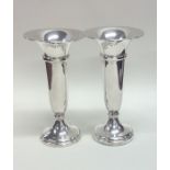 A pair of heavy plain tapering silver spill vases.