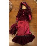 A dressed porcelain headed doll in crimson gown. E