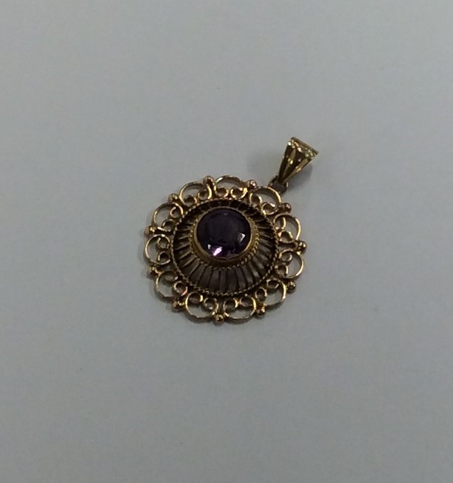 A 9 carat circular amethyst pendant with loop top.