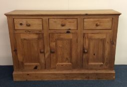 A stripped pine three drawer sideboard on pedestal