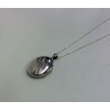 A silver engraved locket on fine link chain. Appro