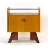 A 1960's oak bedside cabinet, the black glass shelf over a single door with unusual handle,