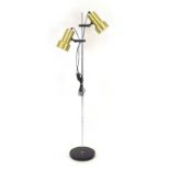 A brass coloured twin-spot adjustable standard lamp with an aluminium shaft and black base