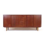 A 1970's Danish teak sideboard with an arrangement of four sliding doors and five drawers,