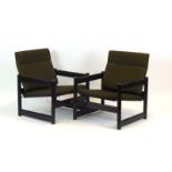 A pair of 1960/70's ebonised armchairs with green loose upholstery and Pirelli rubber supports,