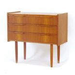 A 1970's Danish teak chest of three drawers on turned legs, w.