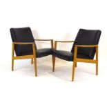 A pair of 1960's Swedish oak framed elbow chairs with black vinyl upholstery