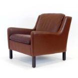 A 1970's low armchair upholstered in red, on mahogany feet,