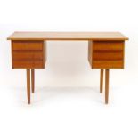 A 1970's teak and crossbanded desk with an arrangement of six drawer on tapering legs, w.
