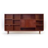 A 1960's Danish teak open bookcase, the centre with a pair of sliding doors on turned legs, w.