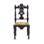 A 19th century figural carved oak side chair with a drop-in seat over a shaped apron on turned legs