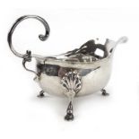 An Edwardian silver sauce boat of traditional form with c-scroll handle on three hoof feet,