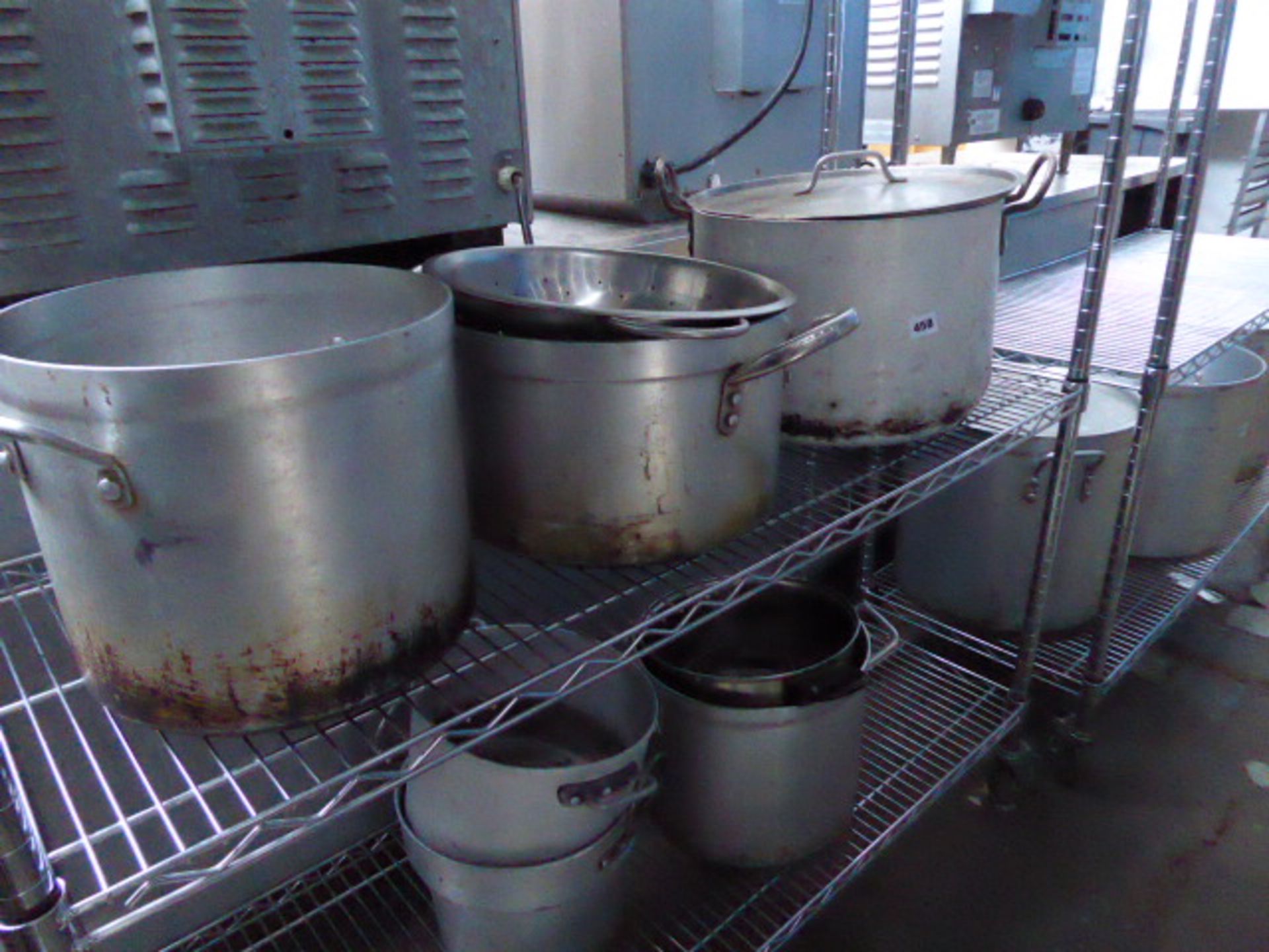 2 shelves of aluminum cooking pots and colanders