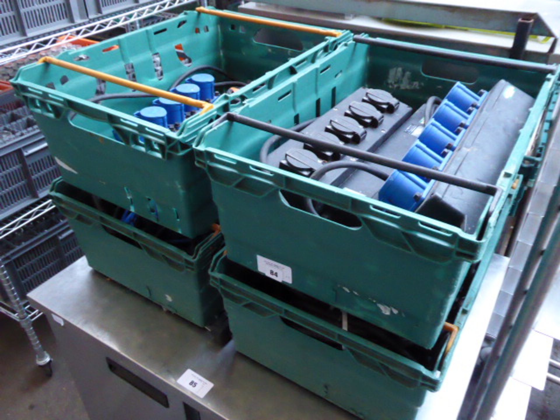 Four plastic trays containing a large quantity of blue commando 240V extension leads and several