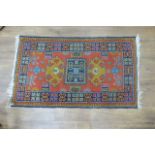 A 20th century woolen rug, the orange ground with geometric medallions, 78 x 136 cm,