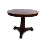 An early 19th century rosewood tilt-top table, the circular surface on a tapering column,