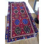 A hand woven Kelim carpet decorated with hexagonal motifs in various shades on a claret ground,