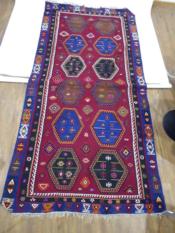 A hand woven Kelim carpet decorated with hexagonal motifs in various shades on a claret ground, - Image 2 of 3