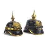 Two miniature First World War German pickelhaube helmets with rigid leather cases and brass mounts,