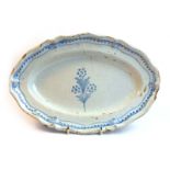 A tin glazed terracotta dish of oval form decorated with blue flowerheads on a white ground, w.
